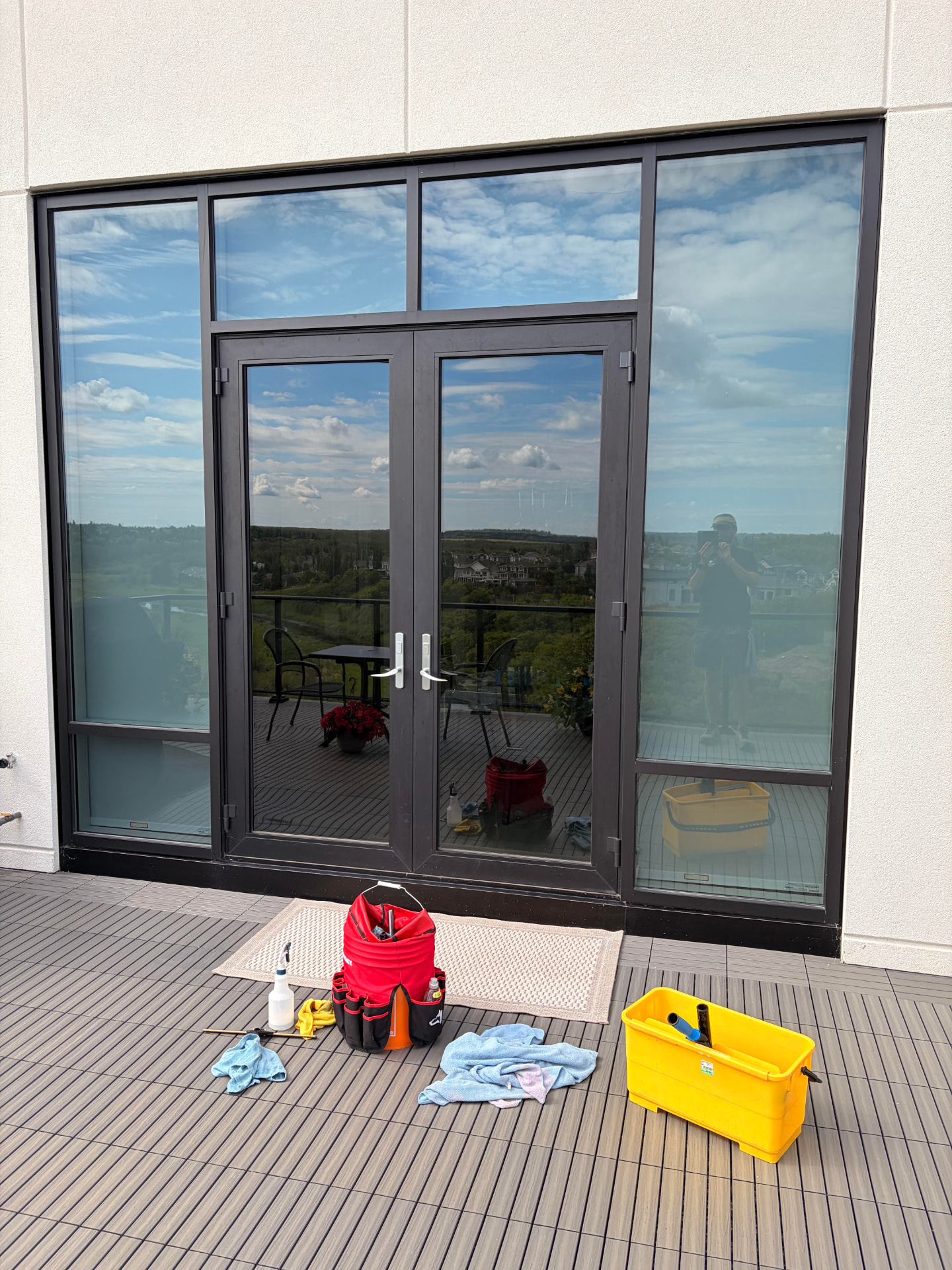 Window cleaning supplies laid out on a balcony in front of glass doors