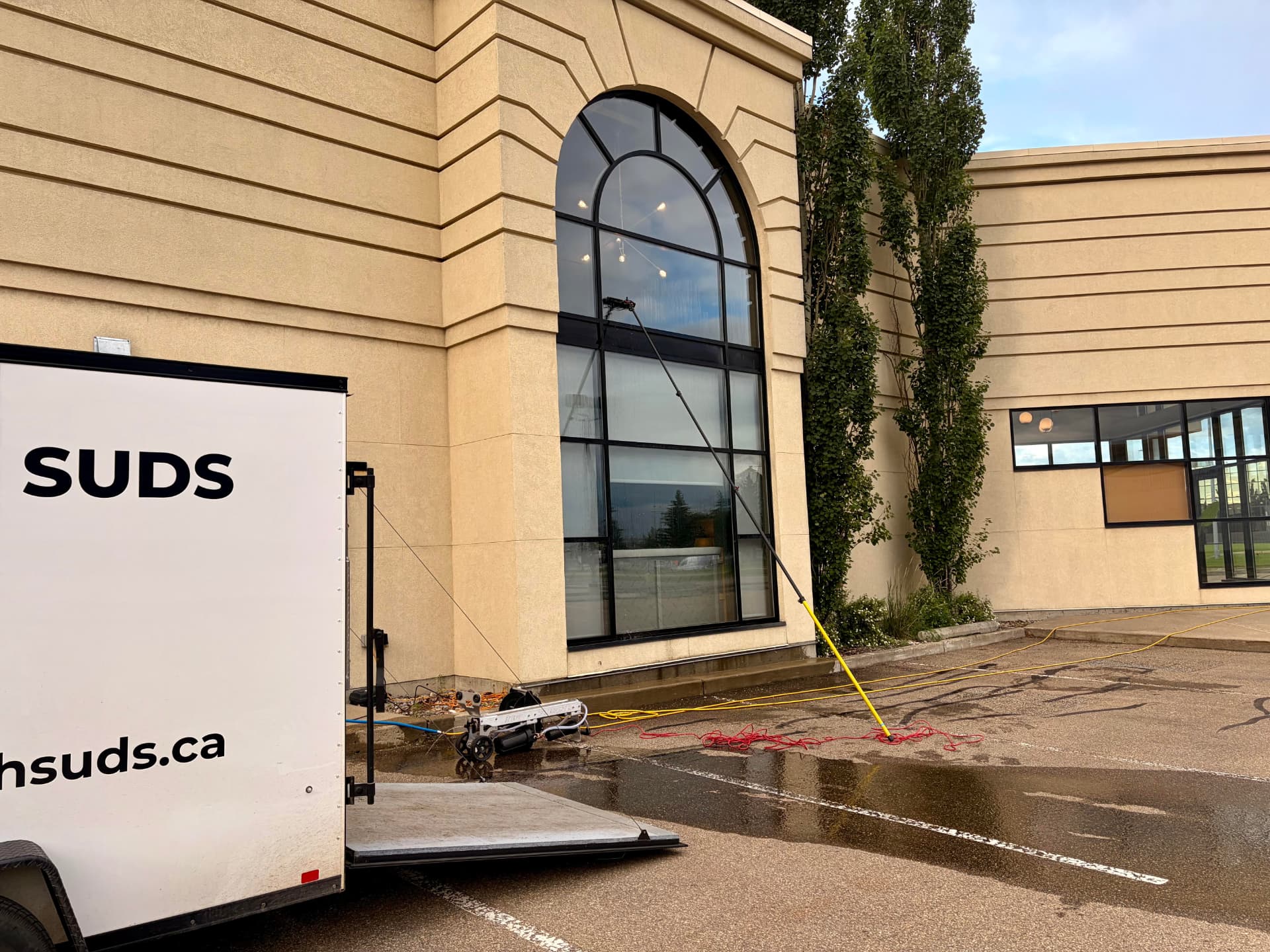Scottish Suds trailer and water-fed pole cleaning a large commercial arched window